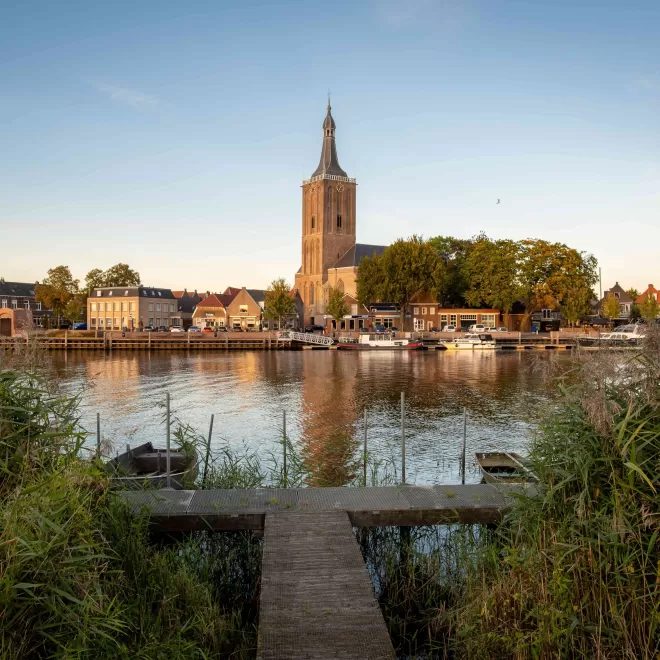 Hasselt gezien vanaf het water, met de grote kerk en een houten steiger op de voorgrond